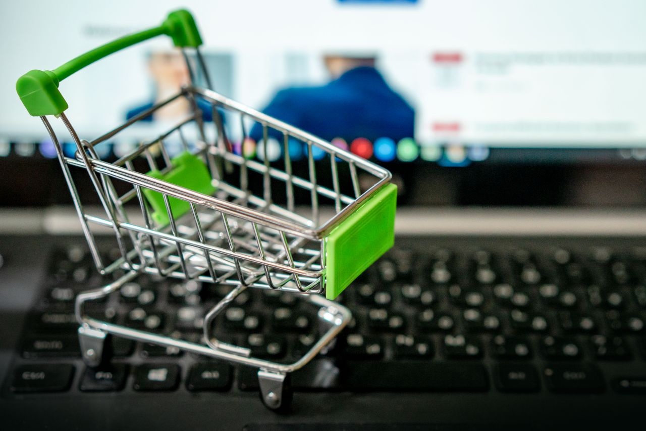 why-choose-us Miniature shopping cart placed on a laptop keyboard, symbolizing online shopping.