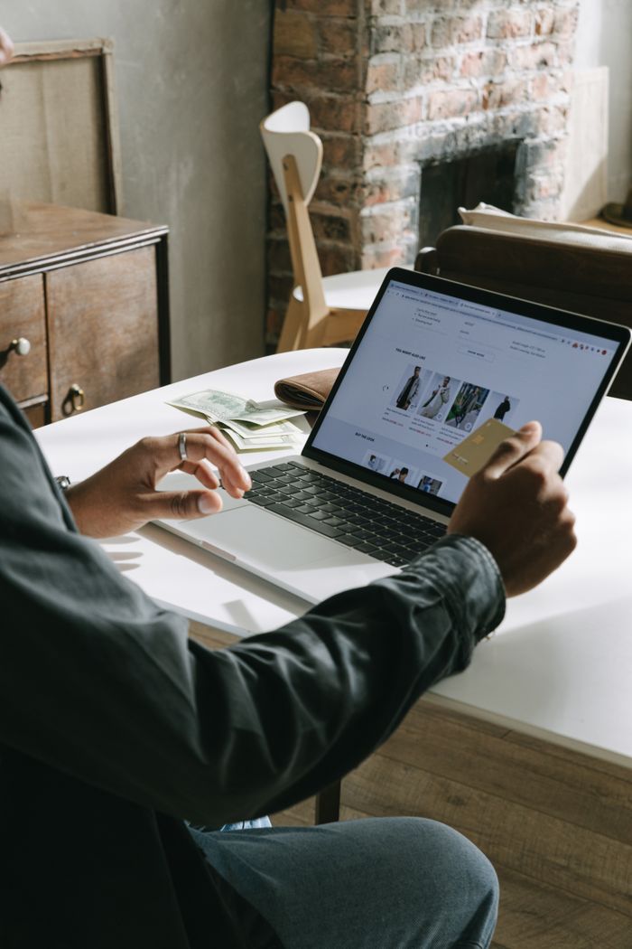 who-we-are An adult uses a credit card for online shopping on a laptop indoors.